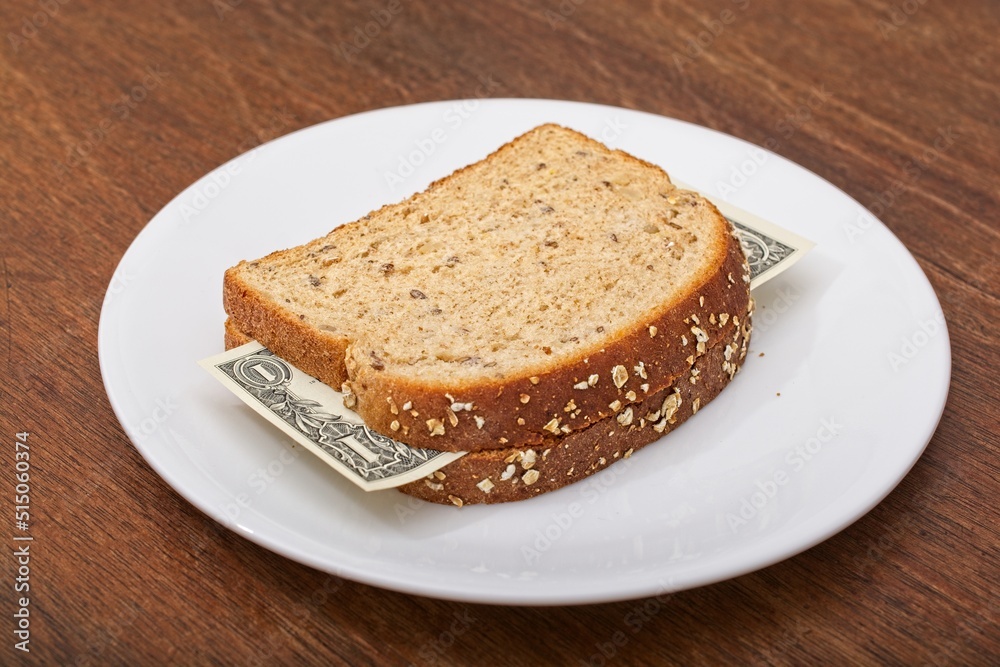 'Consumer staples inflation concept of US dollar bill sandwich with whole grain bread slices on dinner plate'