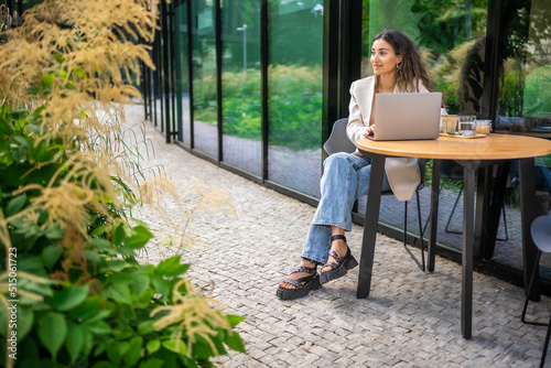 Canvas Print Young smiling brunette business woman in stylish smart dress working on laptop i