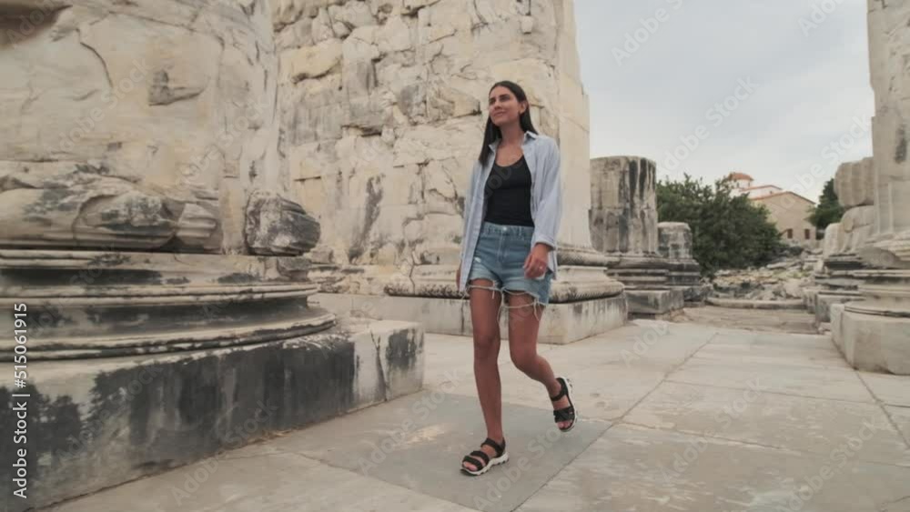 Girl Walking Out from Stone Arch in Ancient Old City Town. Tourist Woman Walks Alone Along Stone columns. Heritage Architecture Area ant Tourist Traveling Trip Girl Walking Out from Stone Arch in Ancient Old City Town. Tourist Woman Walks Alone Along Stone columns. Heritage Architecture Area ant Tourist Traveling Trip