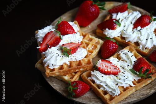 Strawberries with cream on Viennese waffles. Summer dessert with strawberries.