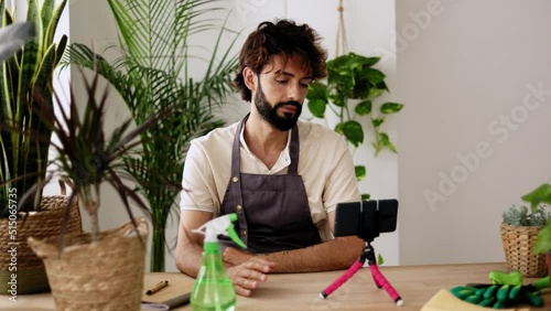 Small business entrepreneur owner of plant shop streaming online from workplace. Young adult content creator influencer blogger recording a video talking about indoor plants care photo