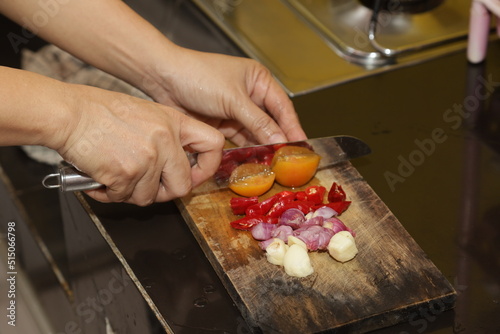 The cook cutting and dice onion on a wooden chopping board. Closeup