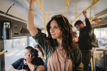 Mid adult woman commuter is standing in bus and travelling in public transport.