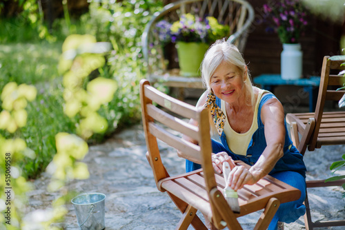 Senior woman cleaning and renovating garden furniture and getting the garden ready for summer