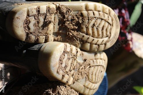 the soles of the boots are dirty by the soil in the garden