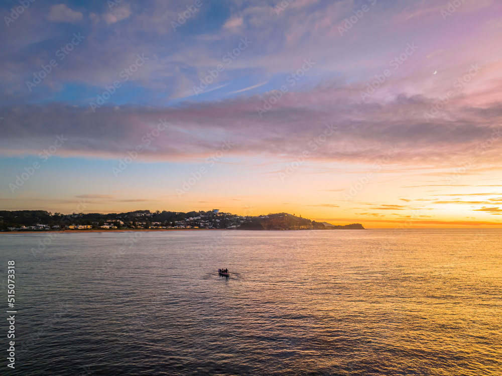 Fototapeta premium Sunrise over the sea with high cloud and surf boat rowers