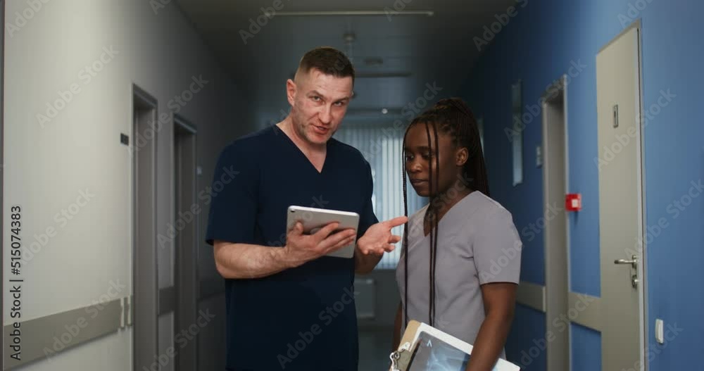A doctor shows his colleague something on a tablet screen A doctor shows his colleague something on a tablet screen