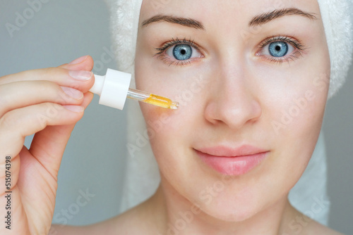 Portrait of young woman holding dropper with serum, skin care concept.