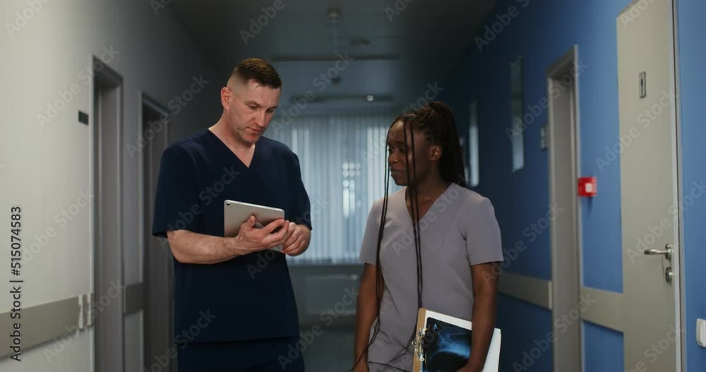 A doctor shows his colleague something on a tablet screen A doctor shows his colleague something on a tablet screen