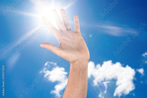 Human hand to sun on sky background