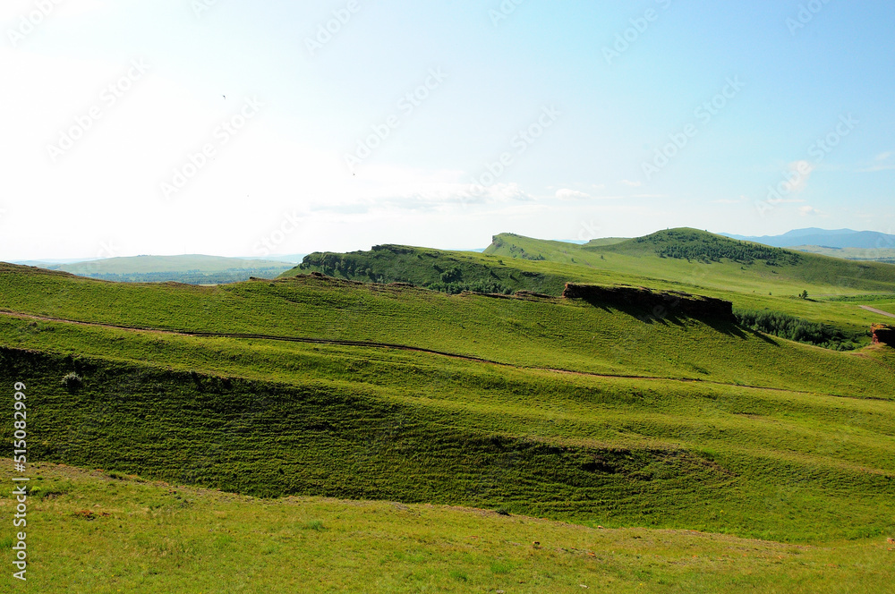 Panoramic shot of the peaks and slopes of a mountain range in a beautiful valley on a sunny summer day. Panoramic shot of the peaks and slopes of a mountain range in a beautiful valley on a sunny summer day.