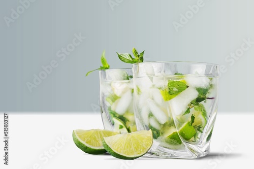 Organic cold refreshing lemonade drink or cocktail made of sparkling water, lime slices and fresh green mint leaves served in drinking glass with ice cubes