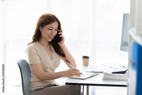 Asian businesswoman in formal suit in office happy and cheerful during using smartphone and working.