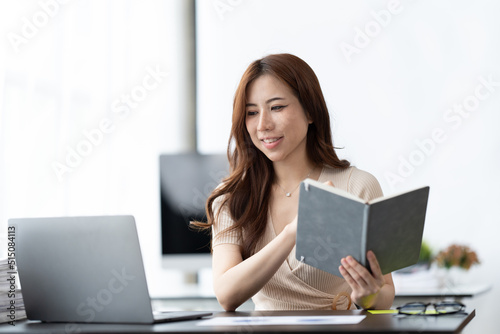 Serious beautiful young woman typing on laptop in a bright modern office, Charming asian businesswoman sitting working on laptop in office.