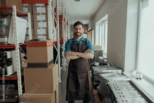 Portrait of rman in uniform standing on workshop of coffee machines warehouse photo