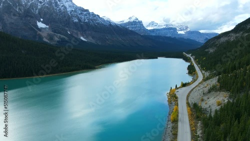 Aerial view of car driving through the forest in national park. Beautiful mountain road near blue clear lake with reflection. Driving on the mountain road. Road trip. Mountain landscape. 