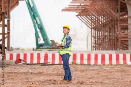 Engineer checking project at the building site, Man in hardhat with laptop at the infrastructure construction site