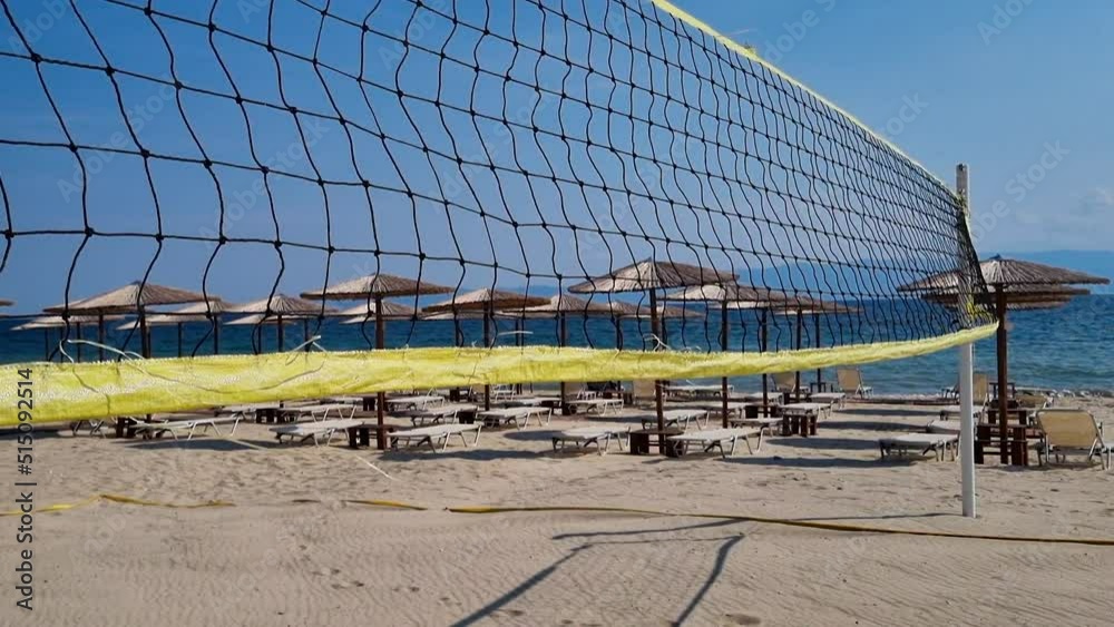 Wind blow beach volleyball net near the sunbeds and straw beach umbrellas. Wind blow beach volleyball net near the sunbeds and straw beach umbrellas.