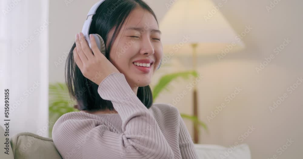 Asian young females relax and enjoy the music they listen to together. women are sitting on the sofa wearing headphones and listening to their favorite songs at home on vacation. Asian young females relax and enjoy the music they listen to together. women are sitting on the sofa wearing headphones and listening to their favorite songs at home on vacation.