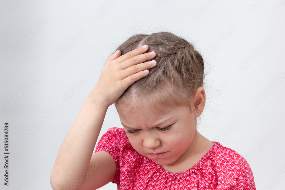 Child with headache holding hand on head on white background caucasian little girl of 5-6 years in red looking down Child with headache holding hand on head on white background caucasian little girl of 5-6 years in red looking down