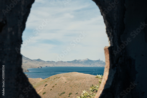 The sea and the rocks on the south coast. Crimea, landscape on a sunny day. View through a hole in the wall. Front view.