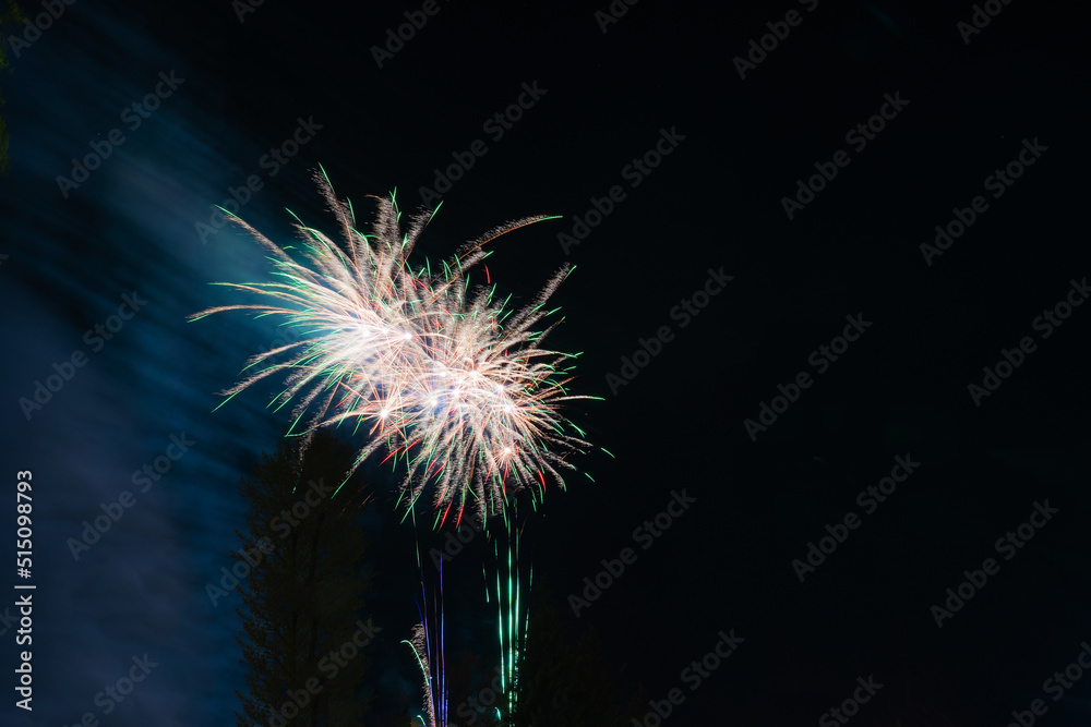 Bright and beautiful festive fireworks of white and green, with haze, in the night sky