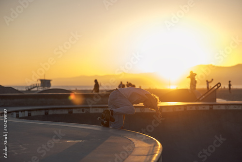 Fotografie Skater jumps ollie trick in skatepark ramp pool bowl on a skateboard at Venice s