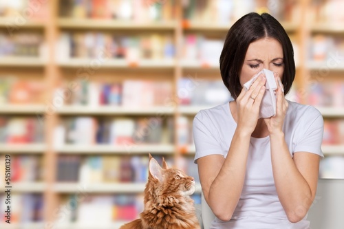 Pet allergy concept. Younglady sneezing and holding paper tissue, suffering from nasal congestion and runny nose sitting on sofa at home