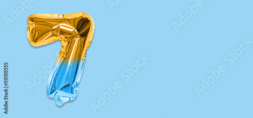 Rainbow foil balloon number, digit seven on a blue background. Birthday greeting card with inscription 7. Top view. Numerical digit. Celebration event, template. Banner