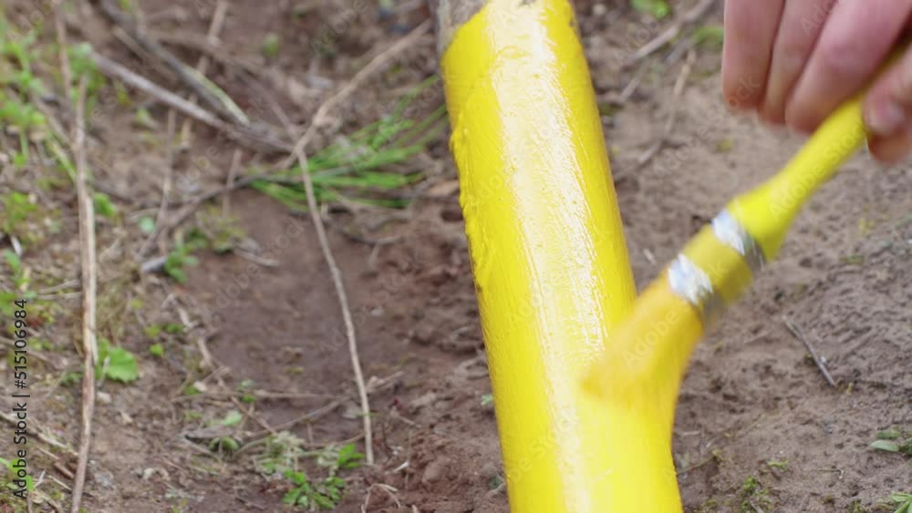 Close-up of a paintbrush carefully painting a pipe with yellow paint. The concept of protecting metal from corrosion, rust prevention. Household works, maintenance and repair of plumbing. UHD 4K. Close-up of a paintbrush carefully painting a pipe with yellow paint. The concept of protecting metal from corrosion, rust prevention. Household works, maintenance and repair of plumbing. UHD 4K.