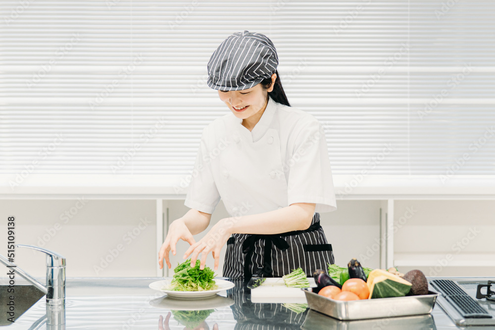 キッチンで野菜を盛り付ける調理師の女性
