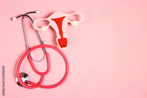 Women's health awareness concept. Uterus symbol with stethoscope on pink background. Diagnostic and research women's reproductive system. photo