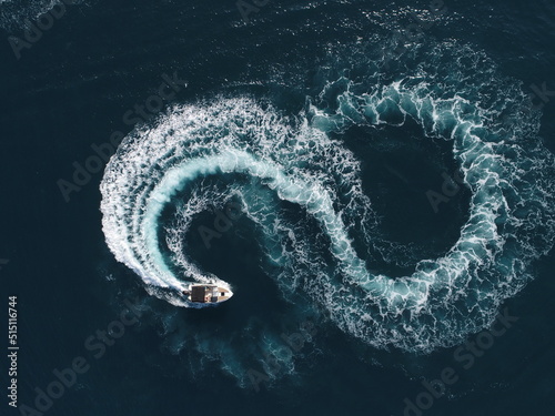 Aerial top view of a white pleasure boat on a summer day. Powerboat turn loop eight on the sea making metaverse infinity future concept.  photo
