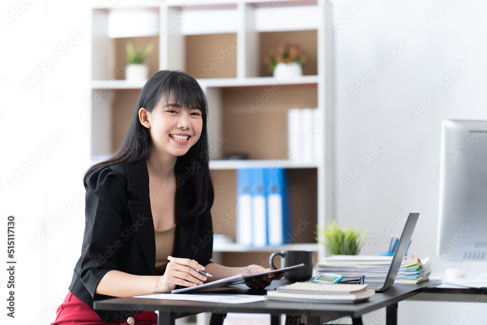 Successful business woman working at the office, business woman sitting by the table with laptop and looking at camera in office.