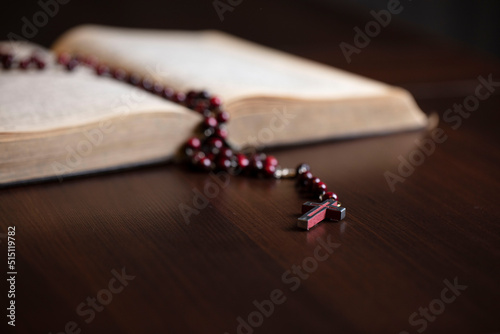 Christianity theme – prayer. Christian woman with Bible praying with hands crossed keeping rosary.