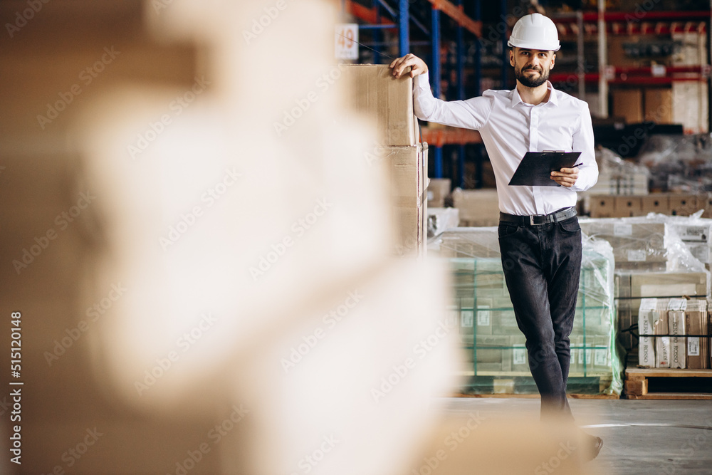 Obraz premium Business man wearing helmet walking in storage