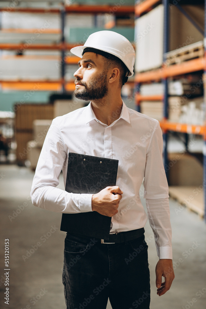 Business man wearing helmet walking in storage Business man wearing helmet walking in storage
