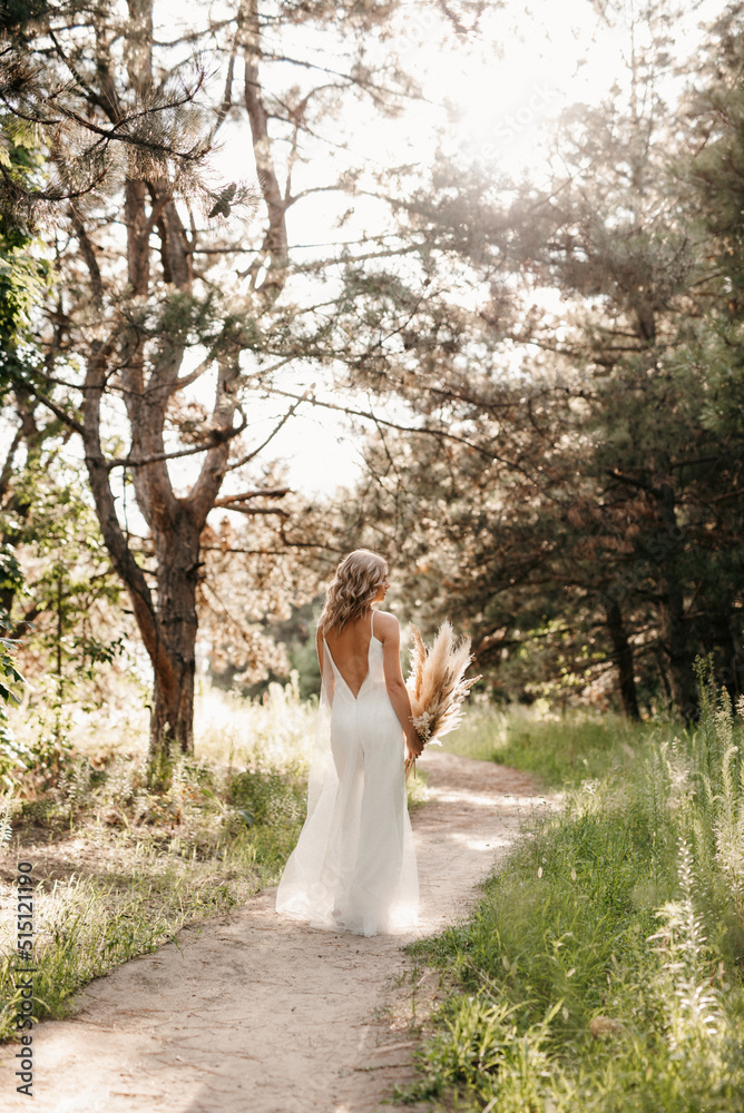 happy bride girl in a white light dress with a bouquet of dried flowers