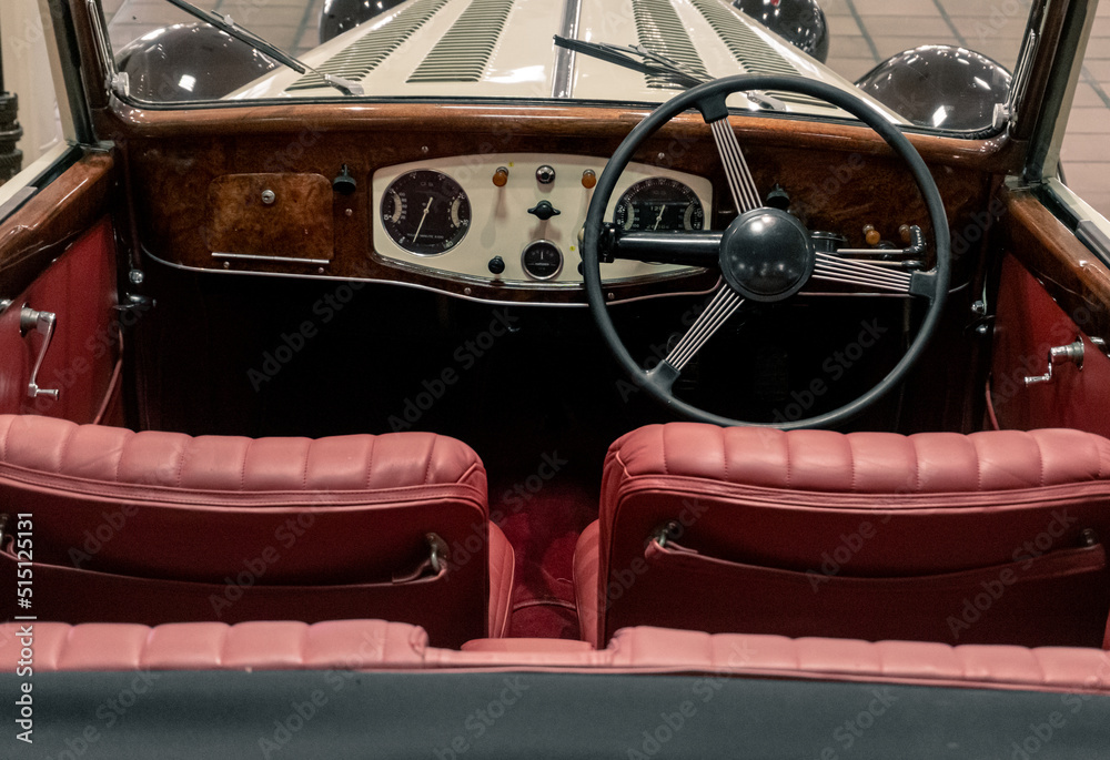 Naklejka premium Monaco, April 2022. Image with the interior of a vintage car, very nicely maintained, with red painted leather seats and large steering wheel on the wooden dashboard.