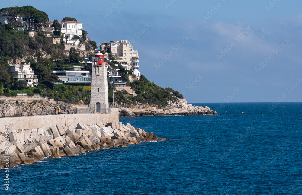 Nice, France, April 2022. Sunny spring picture of the entrance from the harbor. The beauty of the blue sea, lighthouse and colorful buildings built on the mountain.