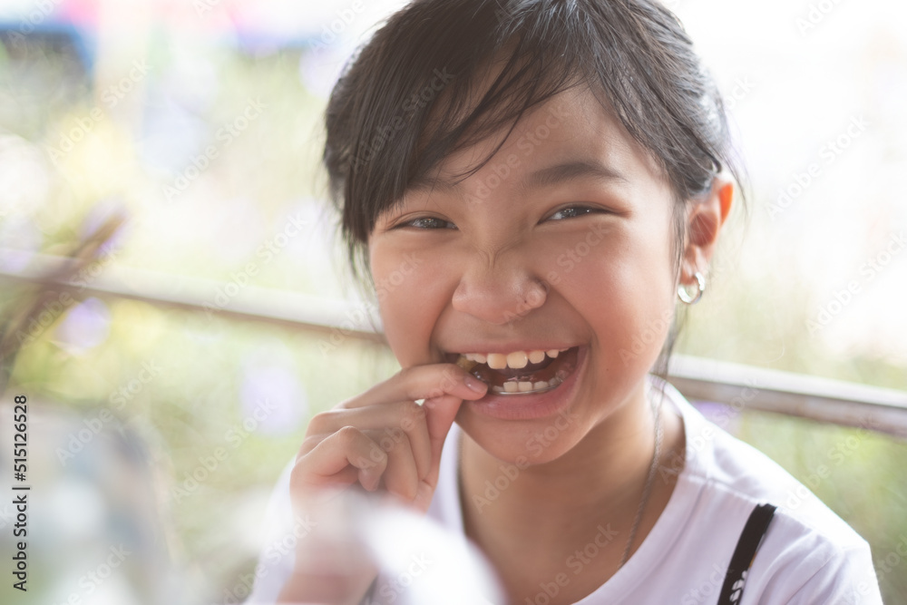 Asian girl eating sweets and smiling in a good mood Asian girl eating sweets and smiling in a good mood