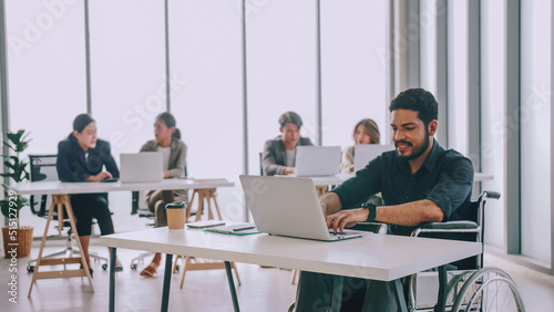 A disabled company employee is able to work happily with colleagues in the office.