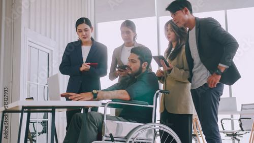 A disabled company employee is explaining a computer program to a group of colleagues.