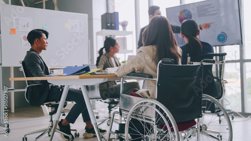 A disabled company employee is able to work happily with colleagues in the office. A group of marketers are having a discussion at the meeting.