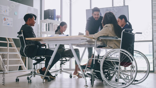 A disabled company employee is able to work happily with colleagues in the office. A group of marketers are having a discussion at the meeting.