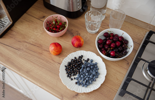Fresh summer berries on beautiful plates. Berries and fruits for a light breakfast in the kitchen. Healthy food. Cherry, cherry, blueberry, currant and nectarine