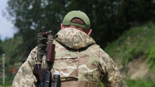 A Ukrainian sniper walks through the woods with a Dragunov sniper rifle on his shoulder. walking soldier sniper rear view. close-up. war in Ukraine. sniper on the range photo