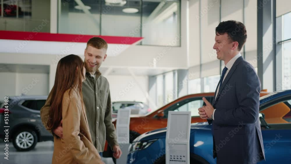 A happy married couple bought a new car. The manager passes the key. On the background of a car dealership A happy married couple bought a new car. The manager passes the key. On the background of a car dealership