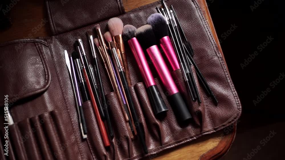 Close-up of make-up tassels that lie in a leather bag. Leather-covered make-up kit on a wooden table. Top view
