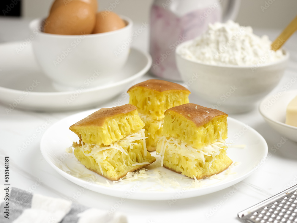 Martabak Keju, Indonesian Traditional Street Food Named Martabak Manis (Sweet Martabak) with Grated Cheese on WhiteTable. Selective focus Martabak Keju, Indonesian Traditional Street Food Named Martabak Manis (Sweet Martabak) with Grated Cheese on WhiteTable. Selective focus
